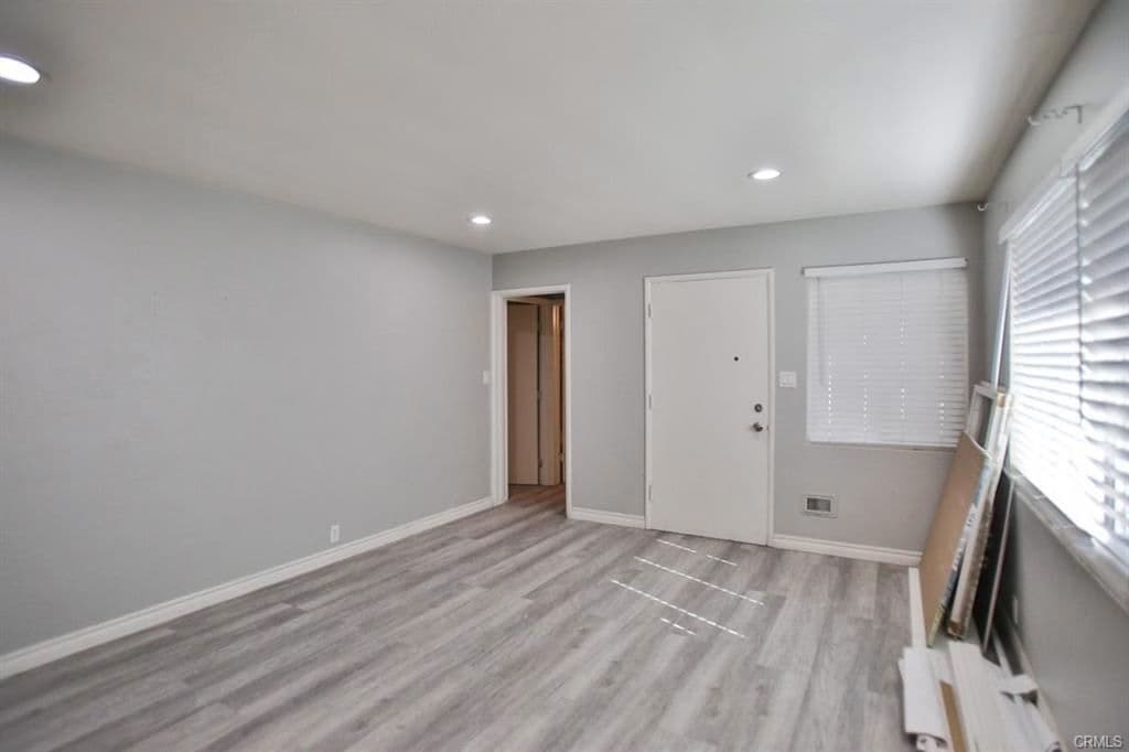 Unfurnished interior room at 525 W Hampshire Ave with grey walls, recessed lighting, wide-plank vinyl flooring and a window with white blinds.